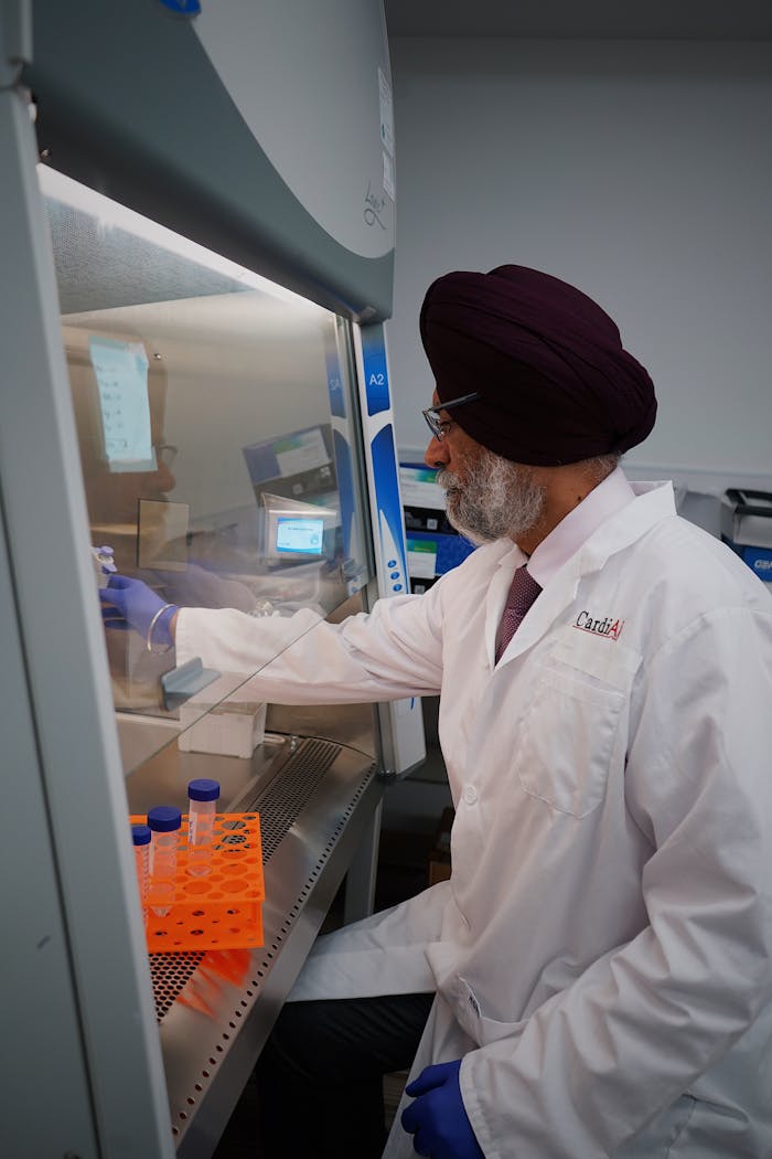 A scientist in a lab coat working at a laboratory workstation with scientific equipment.